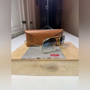 Ray-Ban sunglasses with a gold metal frame and blue gradient glass lenses.